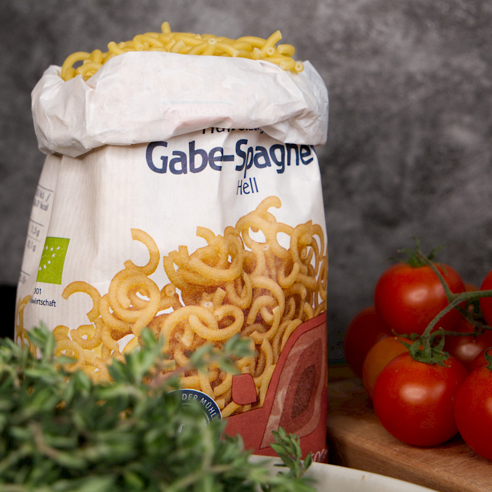 Gabelspaghetti in Papierverpackung mit Frischem Gemüse und Kräutern