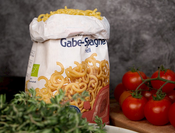 Gabelspaghetti in Papierverpackung mit Frischem Gemüse und Kräutern