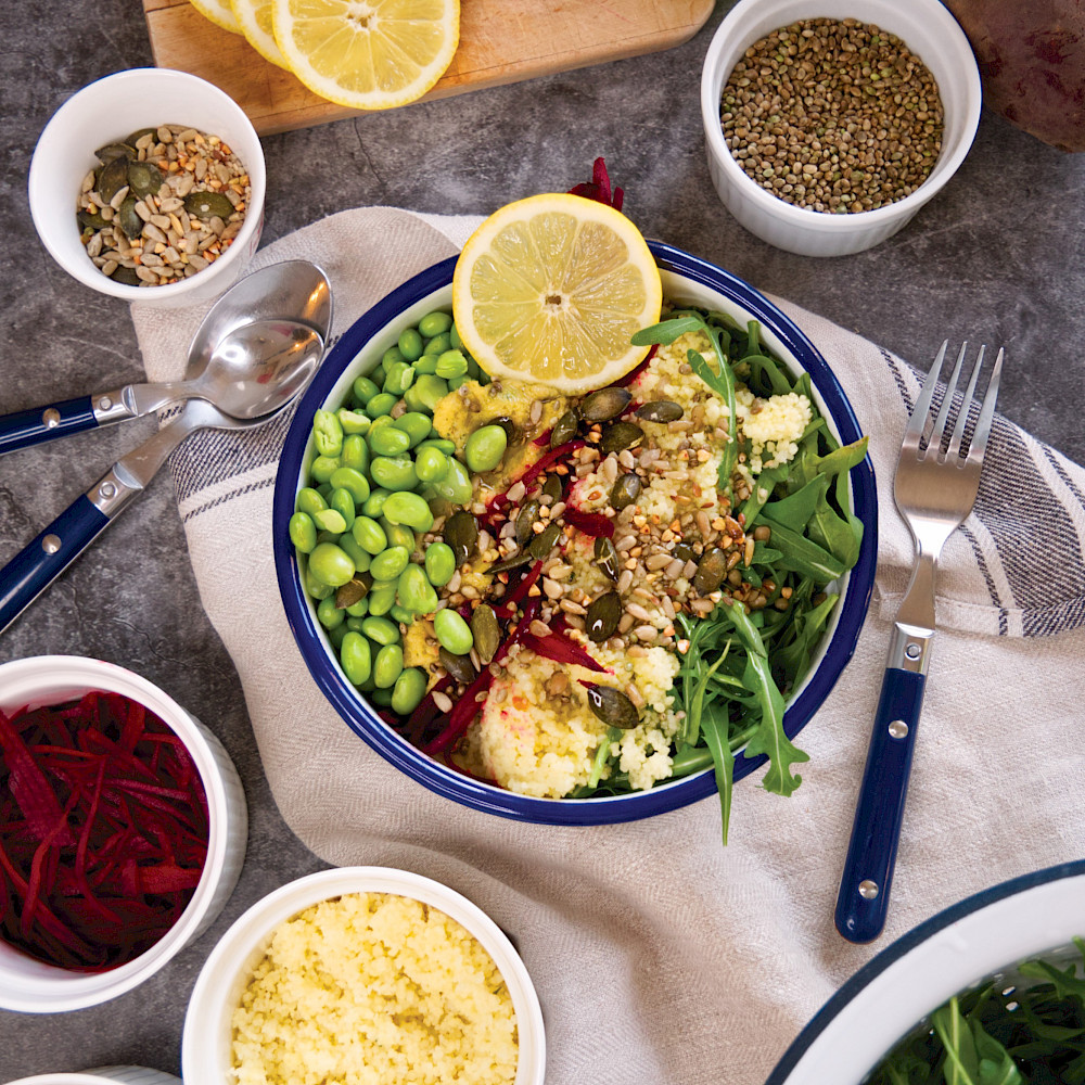 Eine klassische Bowl auf Rucolabasis mit Couscous und Hummus.